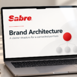 Laptop on a desk displaying the Sabre logo and a Brand Architecture presentation cover.